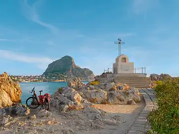 Ein Fahrrad steht im Sonnenaufgang auf der Felsnase 'La Punta' von Sant'Elia.