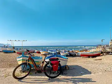 Un vélo est garé dans le village de pêcheurs sicilien d'Aspra, au milieu de bateaux de pêche aux couleurs vives.