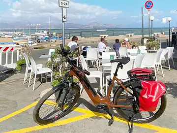 Ein Mietfahrrad von Sicula Bike steht vor einer Bar am Mittelmeer in Aspra.