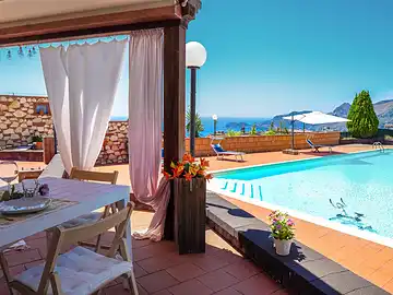 Eine Terrasse mit einem Tisch und Stühlen neben einem Pool.