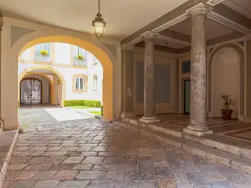 Ein schöner Innenhof mit eleganten Säulen und einem Steinweg, der zu einem ruhigen Garten führt.