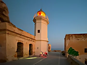 Ein Fahrrad steht kurz vor dem Sonnenaufgang am Leuchtturm des Capo Zafferano.